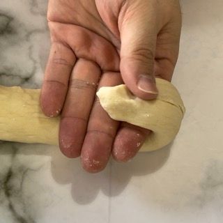 Una persona tiene in mano un pezzo di pasta.