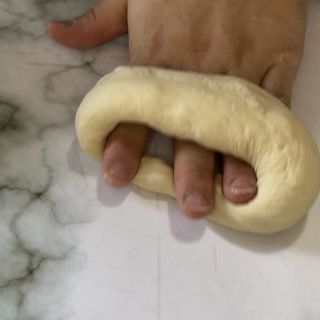 Una persona tiene un pezzo di pasta tra le dita.