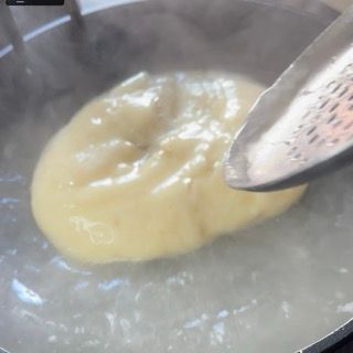 Una ciambella viene versata in una pentola di acqua bollente.