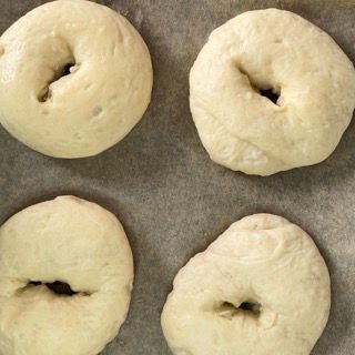 Quattro ciambelle sono appoggiate su un pezzo di carta oleata