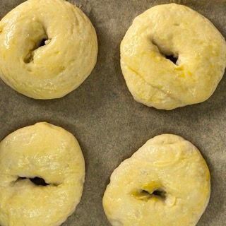 Quattro ciambelle sono appoggiate su un pezzo di carta oleata