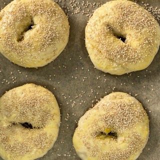 Quattro bagel ricoperti di semi di sesamo su una teglia da forno