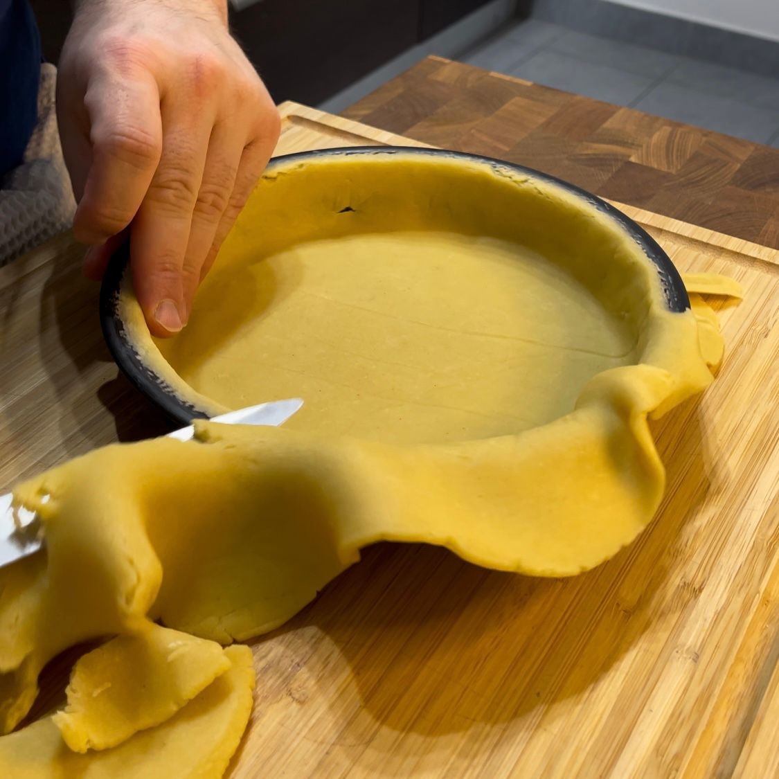 Una persona sta tagliando la pasta di una torta su un tagliere