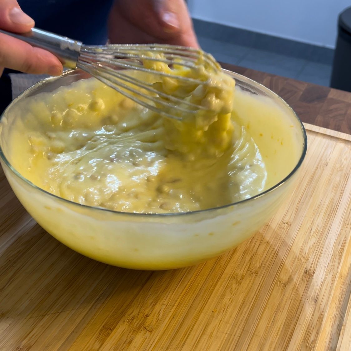 Una persona sta sbattendo qualcosa in una ciotola su un tagliere