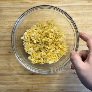 Una persona tiene in mano una ciotola di cibo su un tavolo di legno