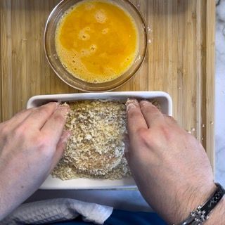 Una persona sta immergendo un pezzo di cibo in una ciotola di uova.