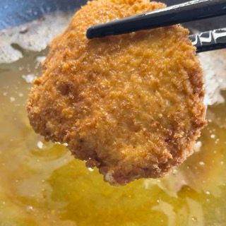 Un pezzo di cibo fritto viene mangiato con le bacchette.