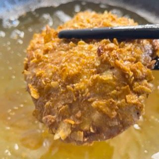 Primo piano di un pezzo di cibo immerso nell'olio con le bacchette.