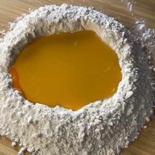 Un mucchio di farina con un liquido giallo nel mezzo