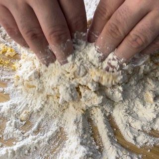 Le mani di una persona sono coperte di farina su un tavolo