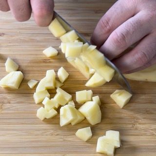 Una persona sta tagliando un pezzo di formaggio su un tagliere