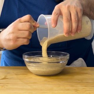 Una persona sta versando qualcosa in una ciotola con un cucchiaio
