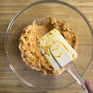 Una persona tiene una spatola sopra una ciotola di cibo.