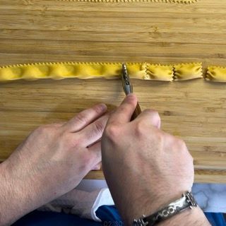 Una persona sta tagliando un pezzo di pasta con le forbici