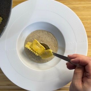 Una persona sta immergendo un pezzo di raviolo in una ciotola di zuppa