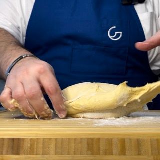 Una persona che indossa un grembiule blu con la lettera g sopra