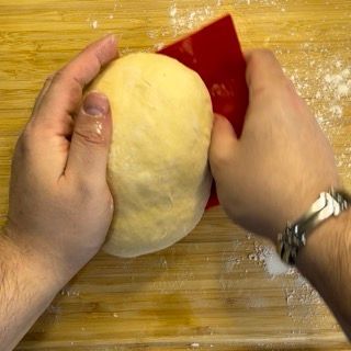 Una persona tiene in mano una palla di pasta e una spatola rossa