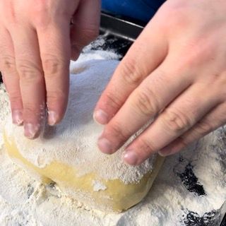 Una persona sta spargendo la farina su un pezzo di pasta