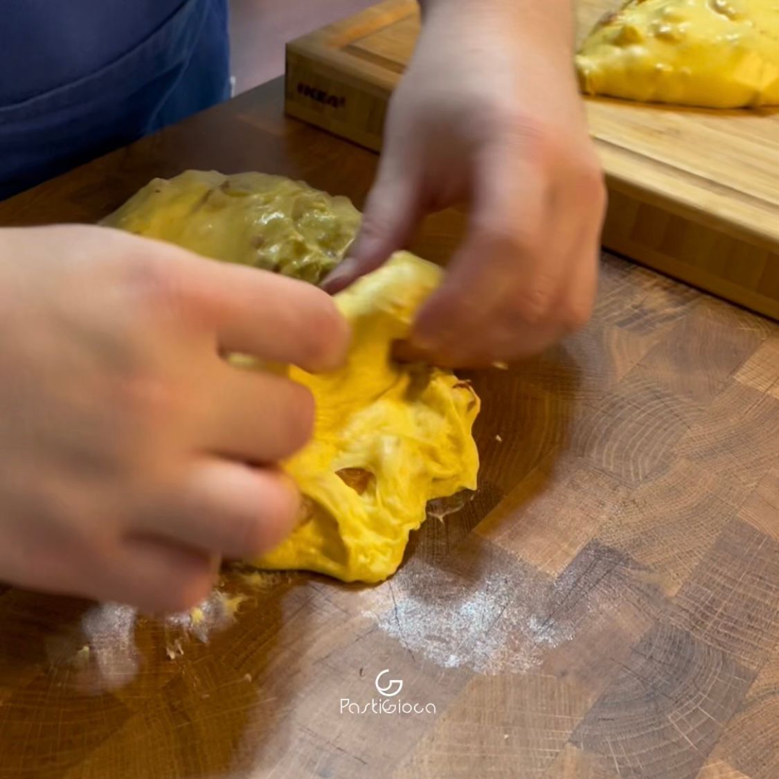 Una persona sta impastando un pezzo di pasta su un tagliere di legno.