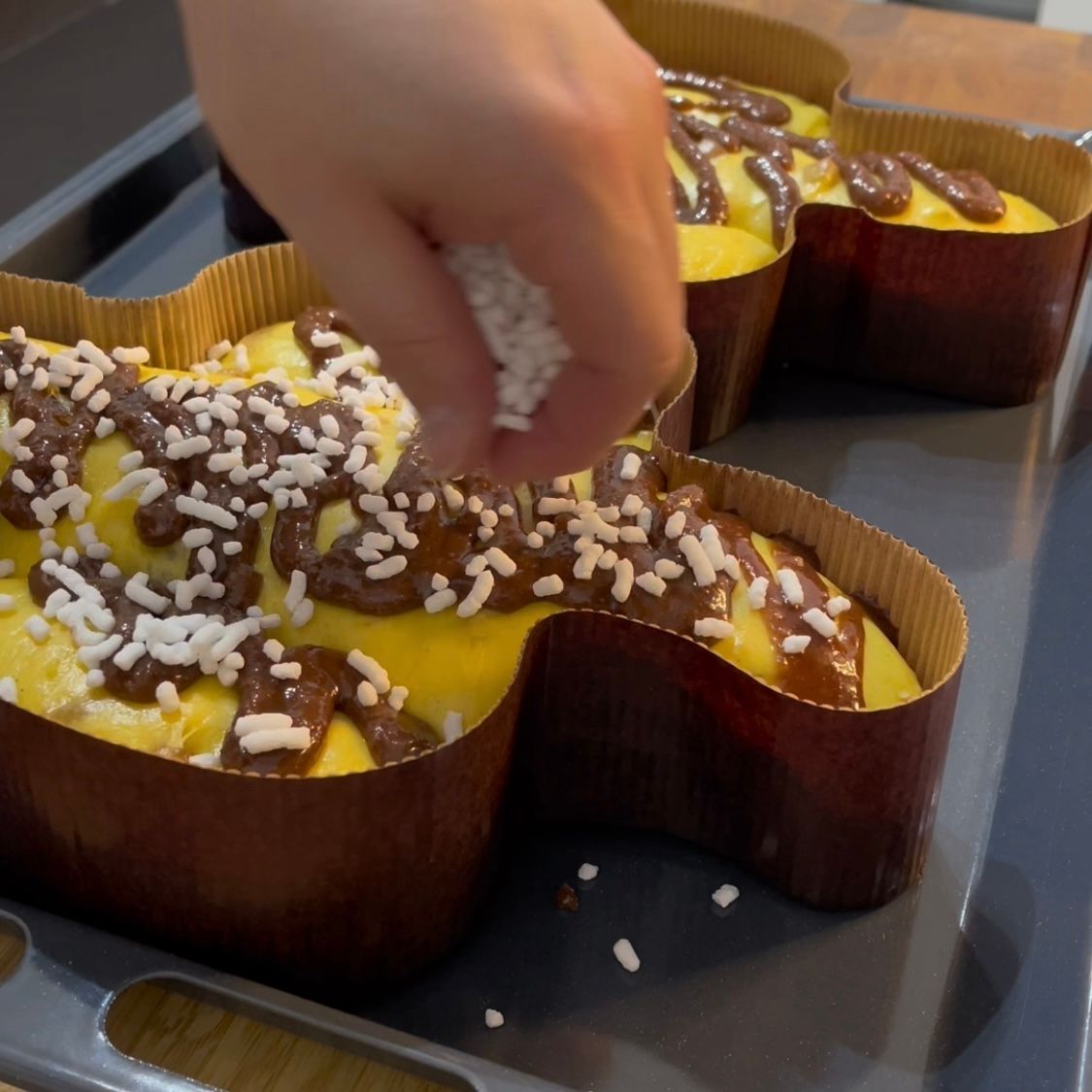 Una persona sta decorando una torta con cioccolato e granelli di zucchero