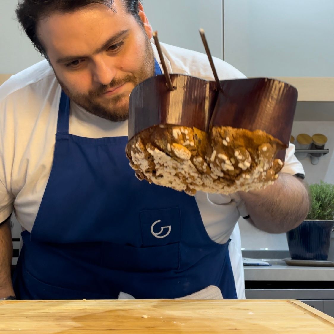 Un uomo con un grembiule blu tiene in mano un pezzo di torta