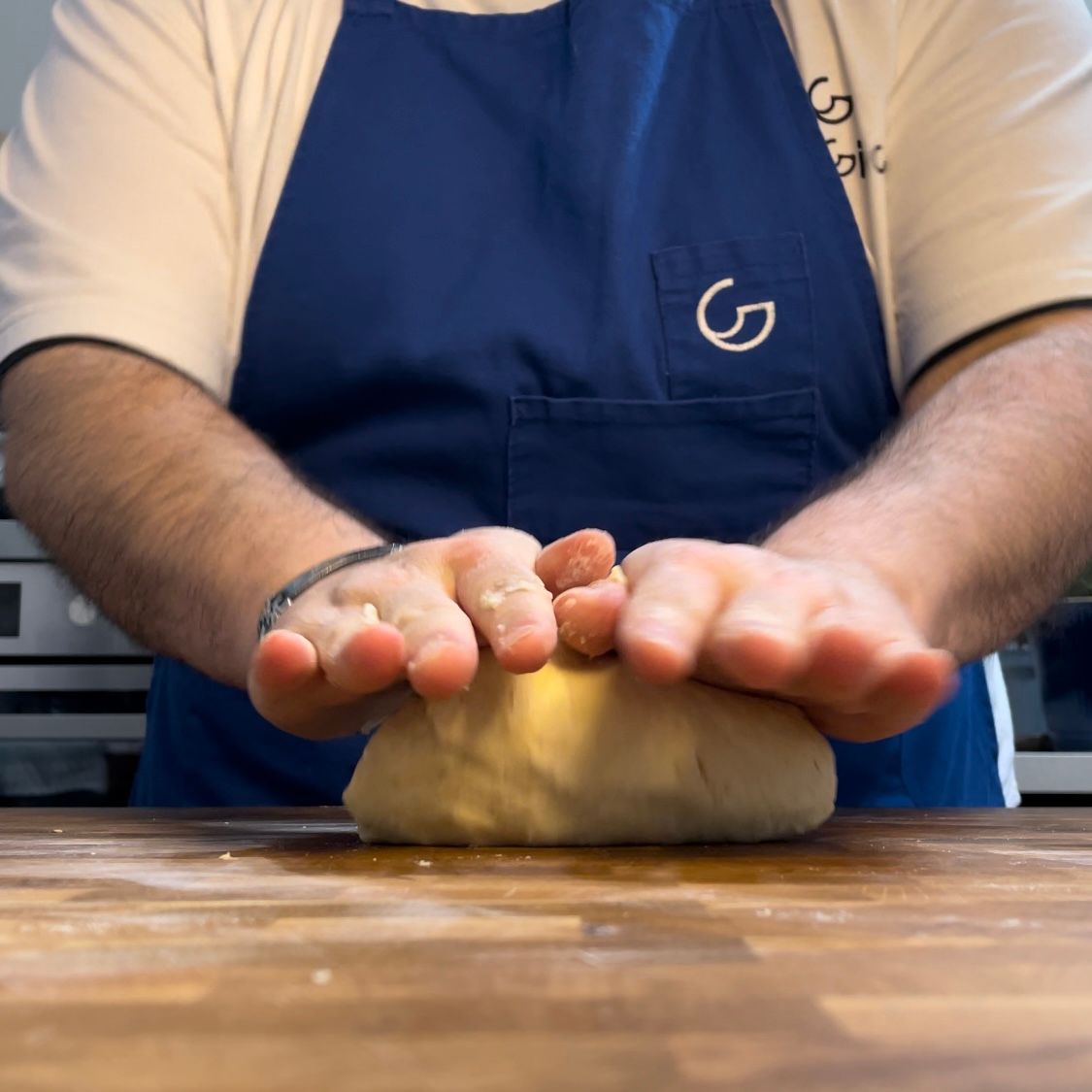 Una persona che indossa un grembiule blu con la lettera g sopra