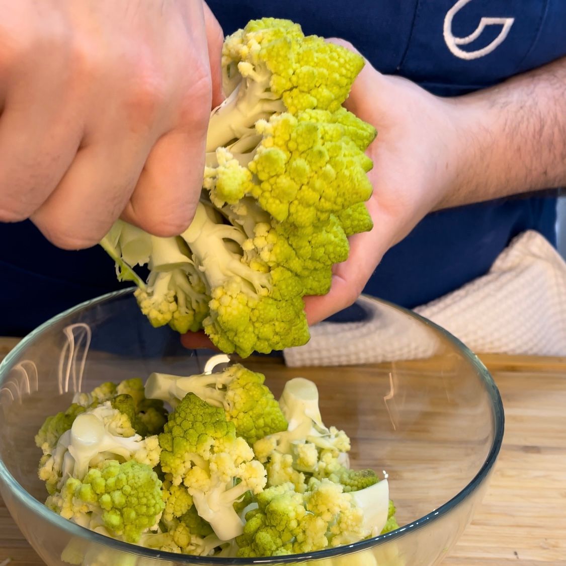 Una persona sta sbucciando il cavolfiore da una ciotola di vetro