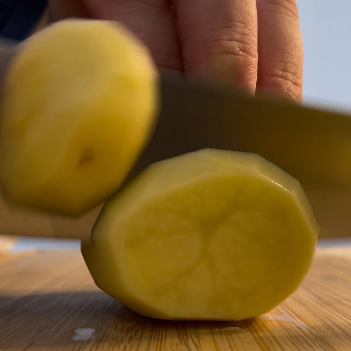 Una persona sta tagliando una patata su un tagliere