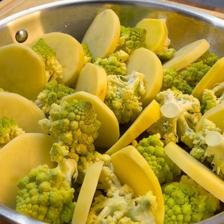 Una ciotola di verdure tra cui broccoli e patate