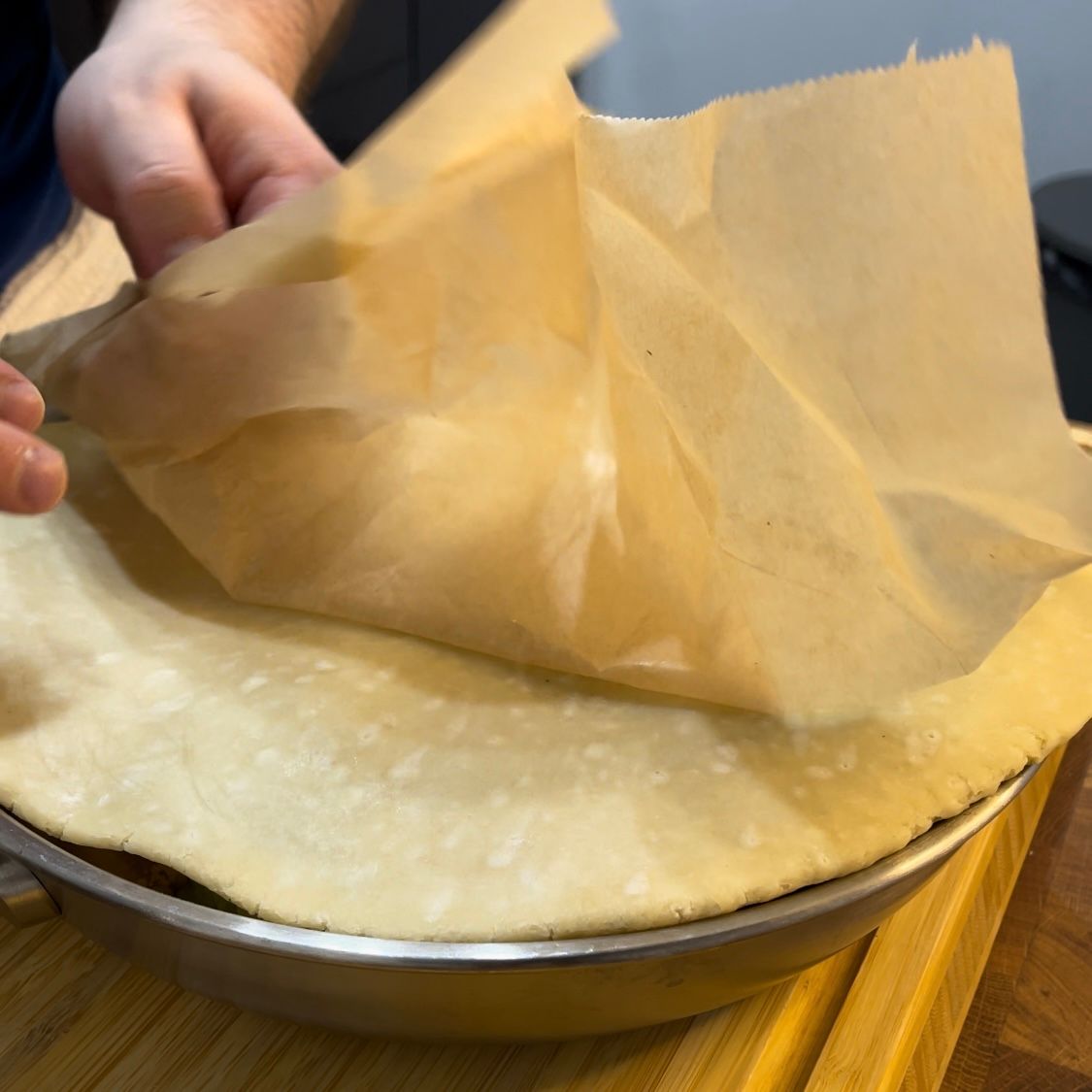 Una persona tiene un pezzo di carta marrone sopra una crosta di torta