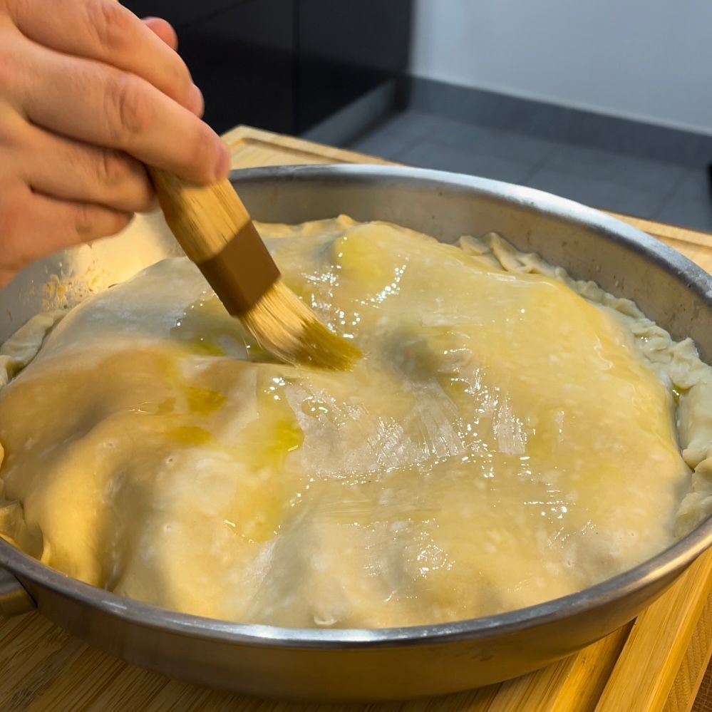 Una persona sta spalmando l'olio su una torta con un pennello.