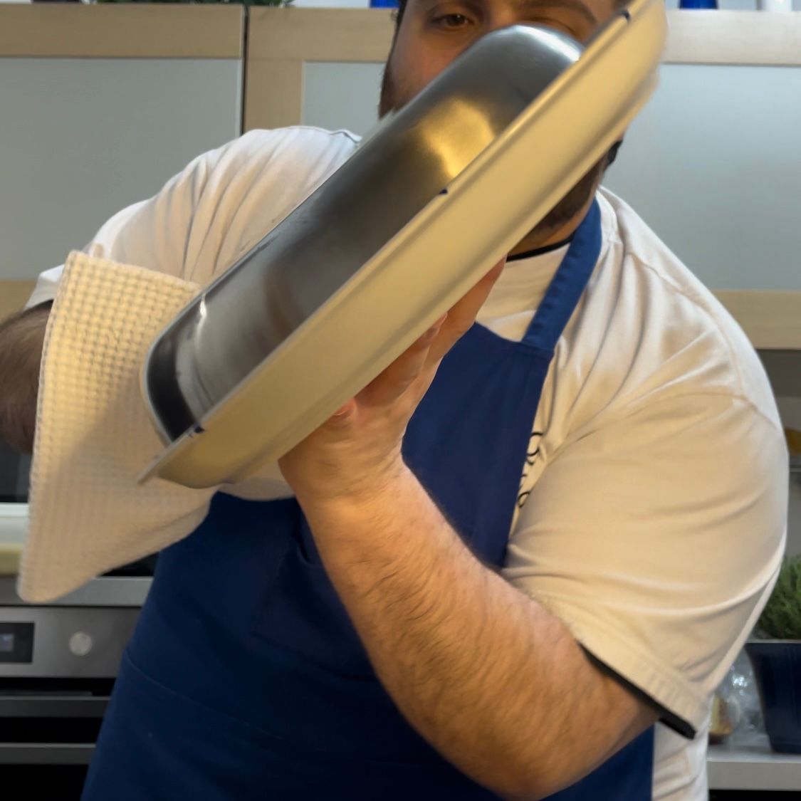 Un uomo con un grembiule tiene una padella in mano