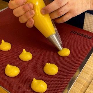 Una persona sta mettendo palline gialle su un tappetino rosso con la scritta pavoni