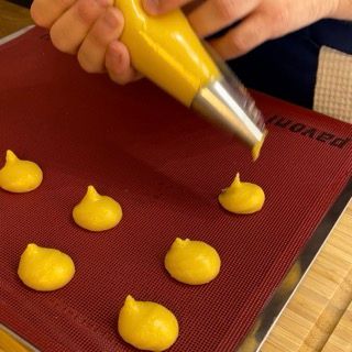 Bignè crudi, formati e ben distanziati sulla teglia.