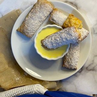 Un piatto bianco con sopra dei pasticcini e una piccola ciotola di crema al limone