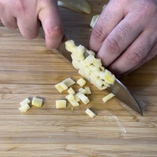 Una persona sta tagliando le verdure su un tagliere di legno