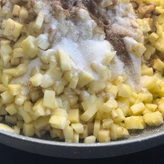 Una padella piena di mele tritate, zucchero e cannella.