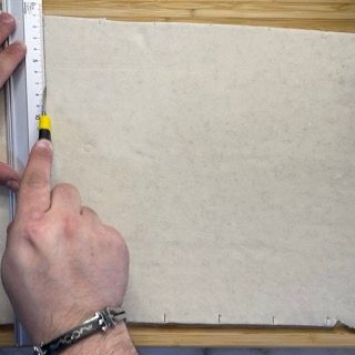 Una persona sta misurando un pezzo di carta con un righello