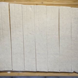 Un tagliere di legno con sopra un mucchio di pezzi di pasta