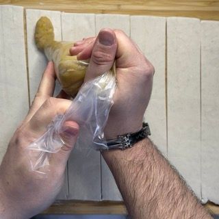 Una persona tiene in mano un pezzo di cibo in un sacchetto di plastica