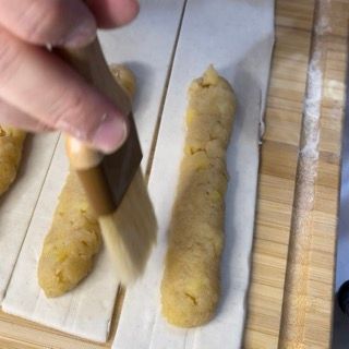 Una persona tiene un pennello sopra un pezzo di pasta