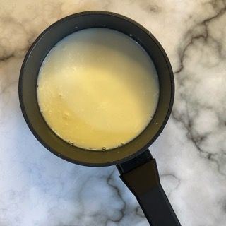 Una pentola nera piena di un liquido giallo su una superficie di marmo