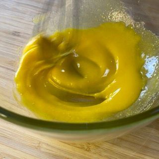 Primo piano di una ciotola di liquido giallo su un tavolo di legno.