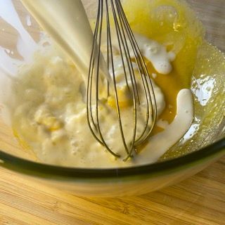 Una frusta è in una ciotola di uova e latte