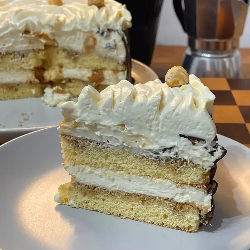 Fetta di Torta Tiramisù senza uova crude che mostra la stratificazione perfetta tra crema, savoiardi e inserto croccante.