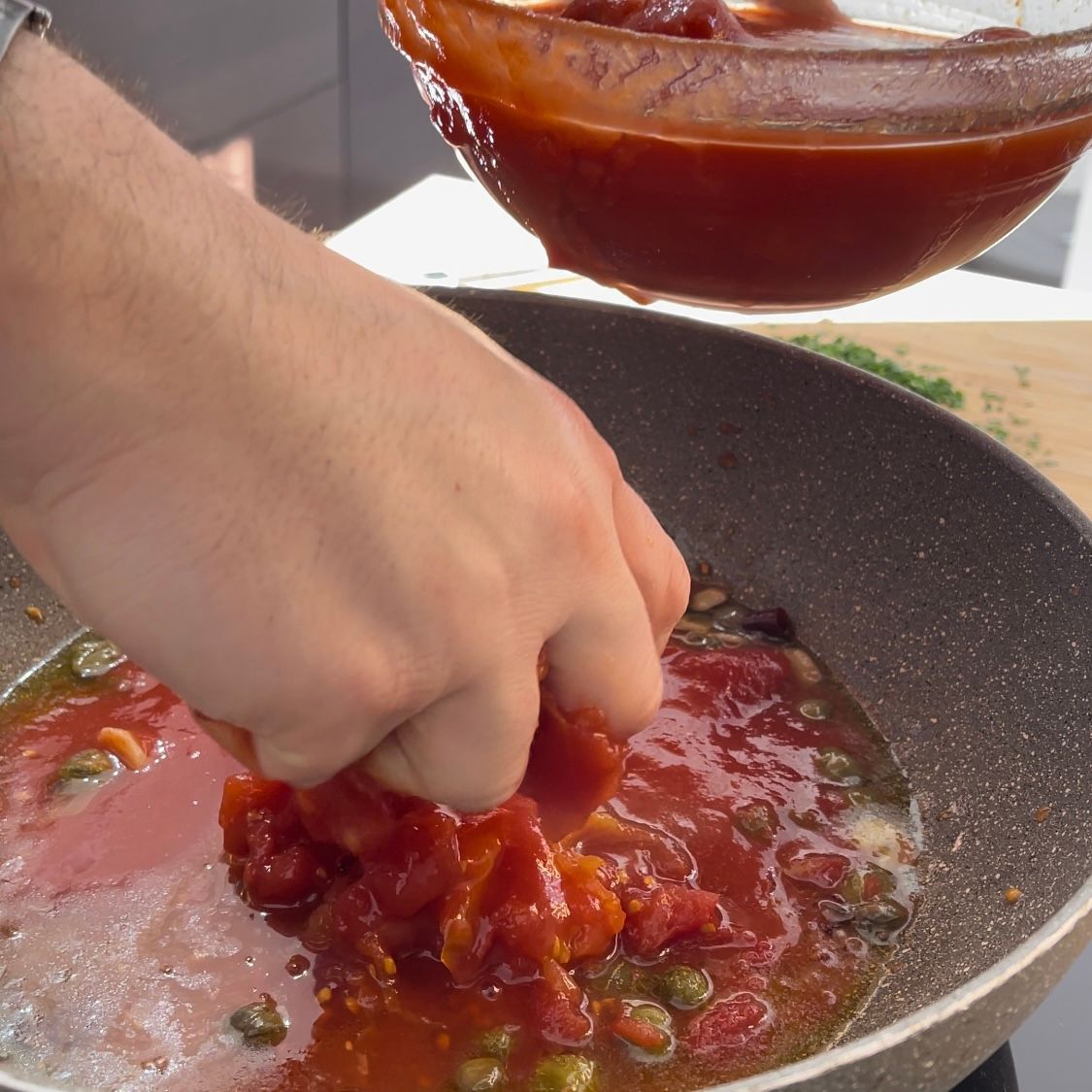 Una persona sta versando la salsa di pomodoro in una padella