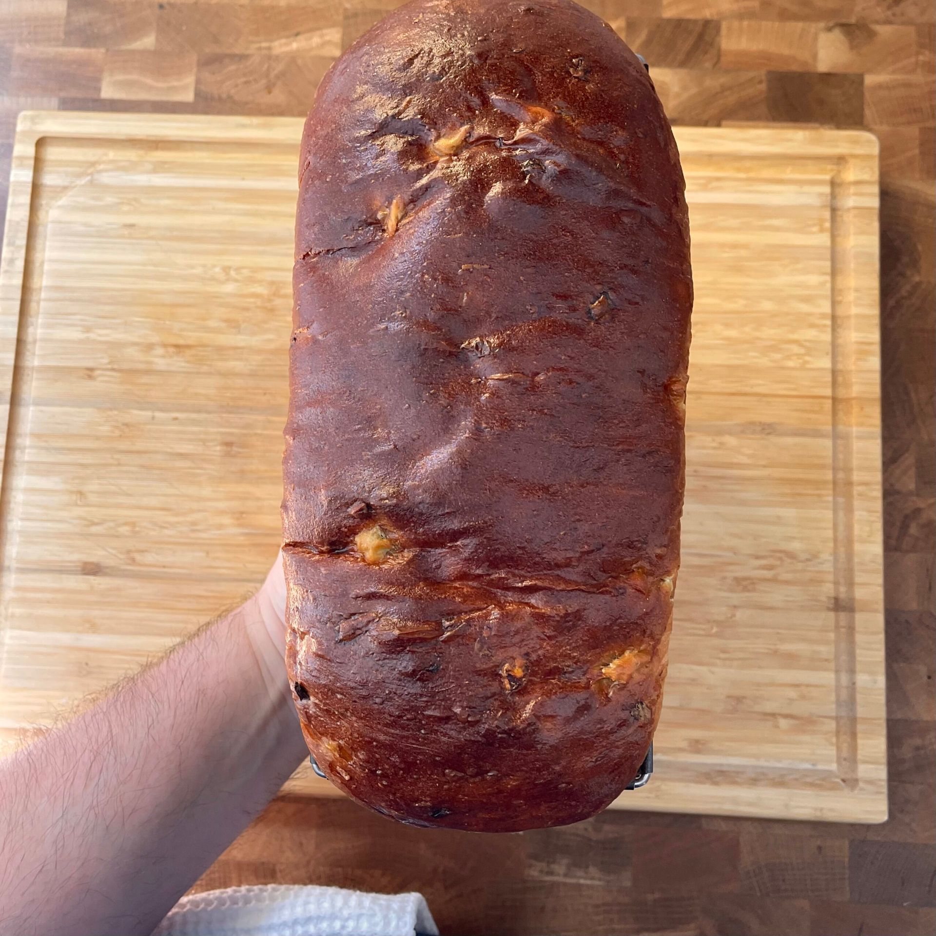 Una persona tiene in mano una pagnotta di pane su un tagliere di legno