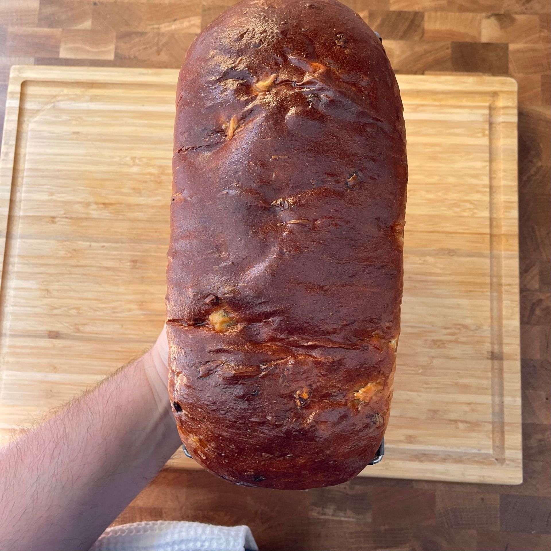 Una persona tiene in mano una pagnotta di pane su un tagliere