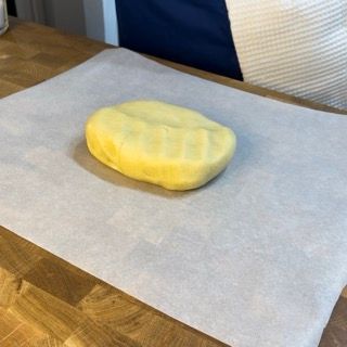 Pasta frolla stesa tra due fogli di carta da forno.