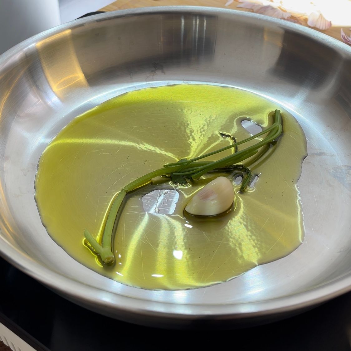 Una padella di acciaio inossidabile piena di olio d'oliva e aglio